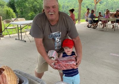 photo of grandfather and grandson holding a rack of ribs