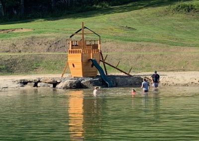photo of wooden pirate ship with a slide into a pond